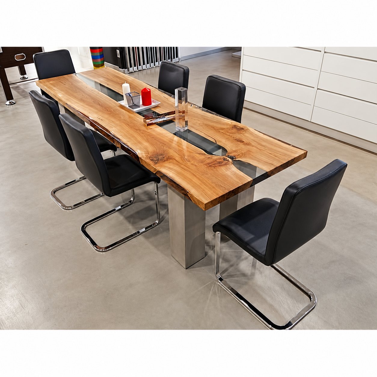 Une longue table en bois massif à veine centrale en résine transparente, entourée de chaises noires à pieds chromés dans un showroom.